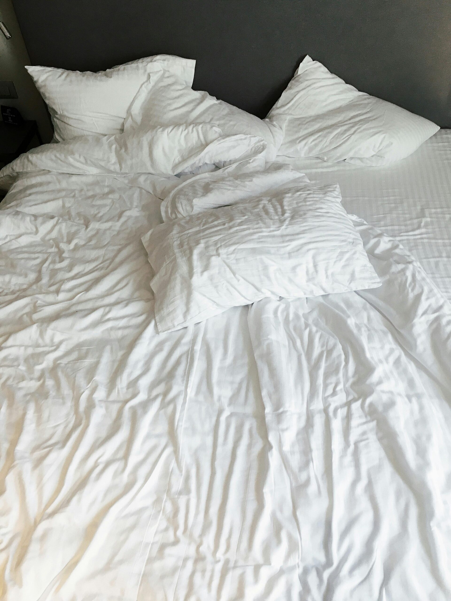 a crumpled up bed with white sheets