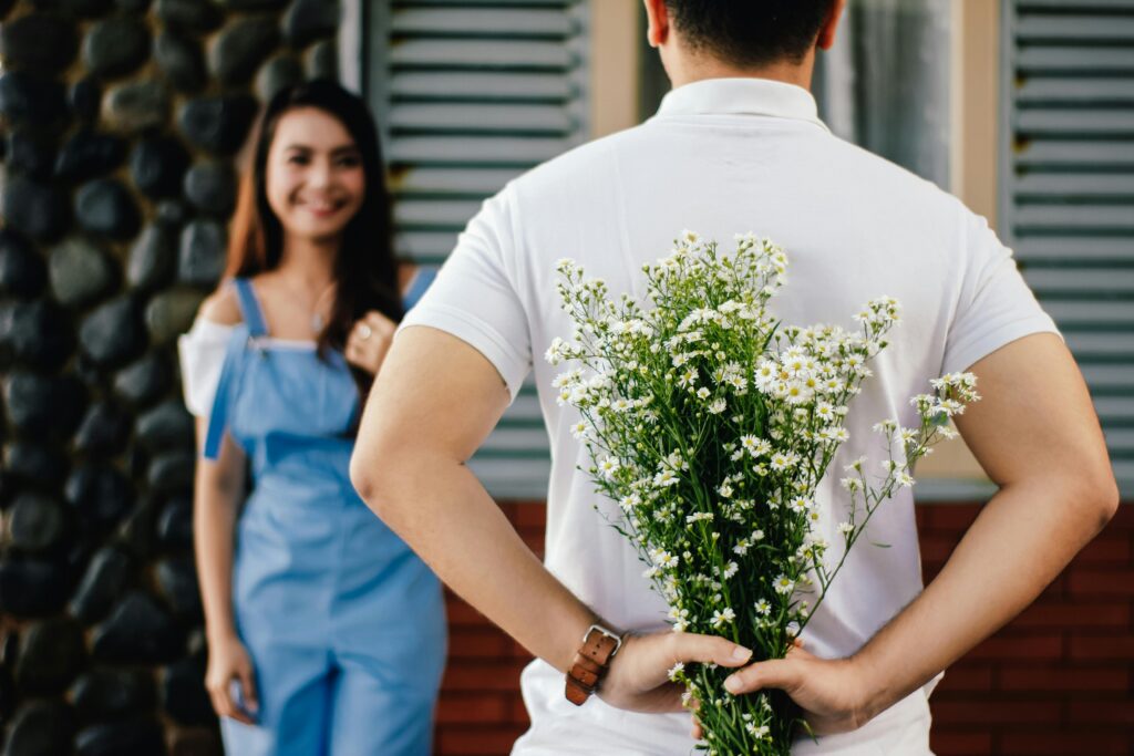 what is emotional cheating? A man hiding a bunch of white flowers behind his back for a woman