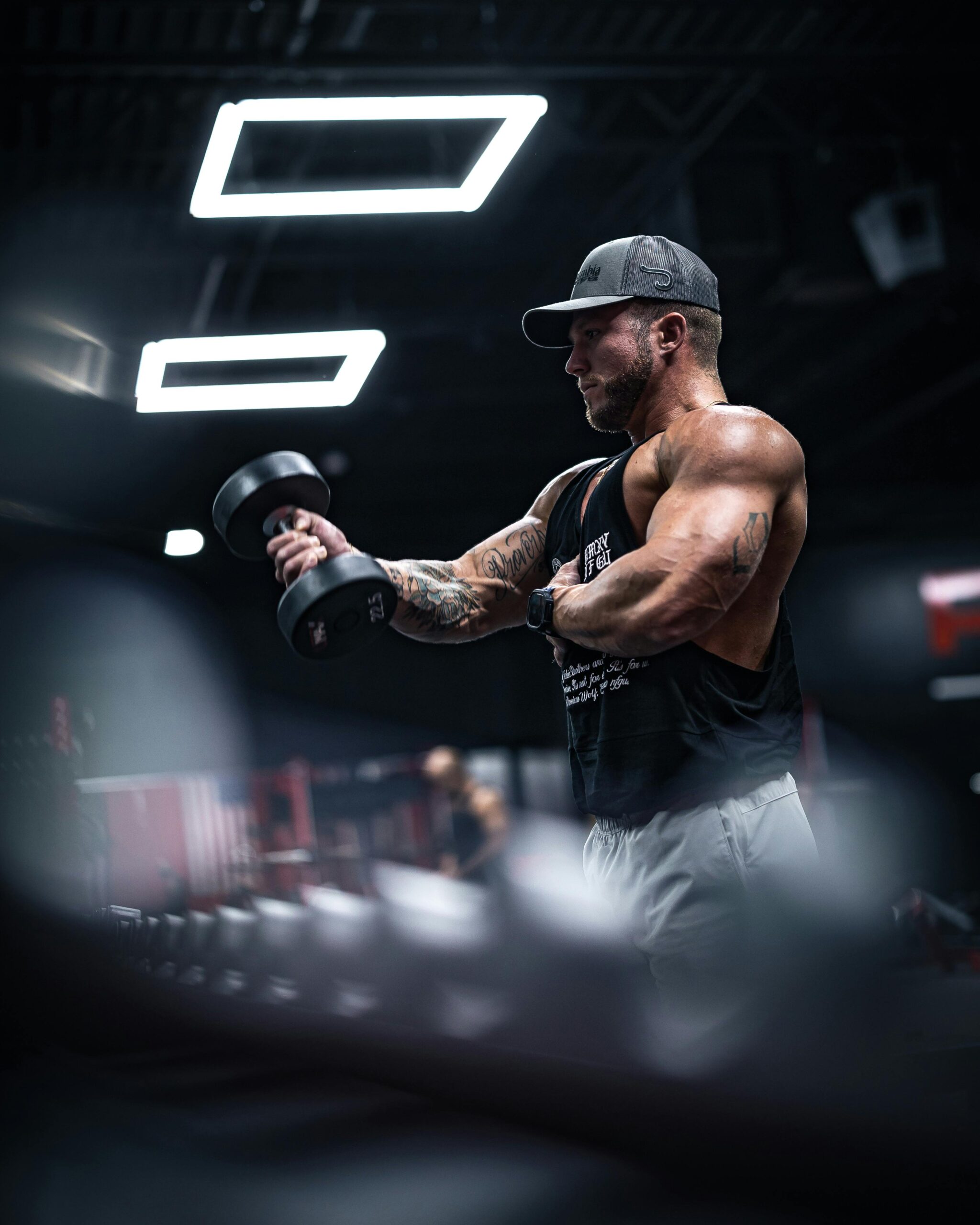 man with big muscles in a dark gym wearing a hat